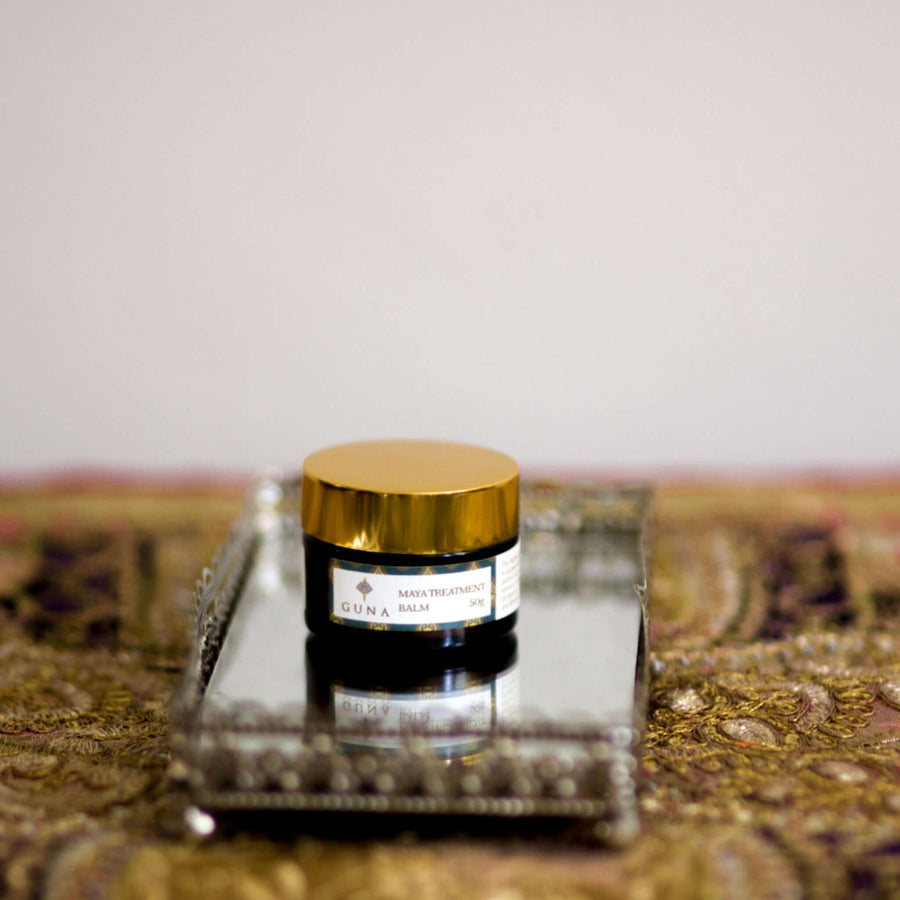 A jar of Guna's Maya Treatment Balm sitting on a mirror tray