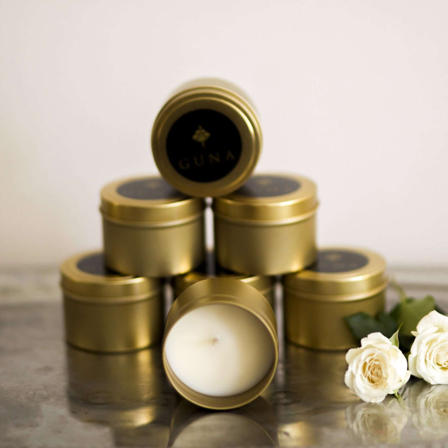 Guna's gold tin candles stacked in a pyramid, with an open candle in front, all placed on a silver tray