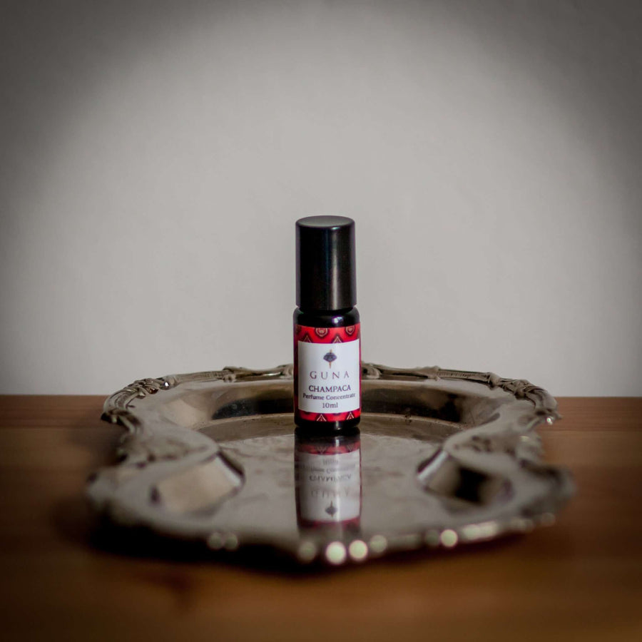 A bottle of Guna's Champaca Perfume Concentrate sitting on a silver tray