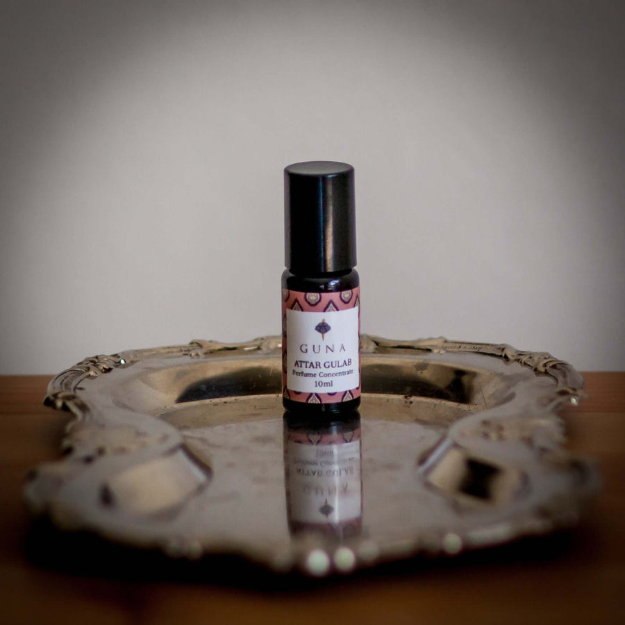 A 10ml bottle of Guna's Attar Gulab Perfume Concentrate sitting on a silver tray